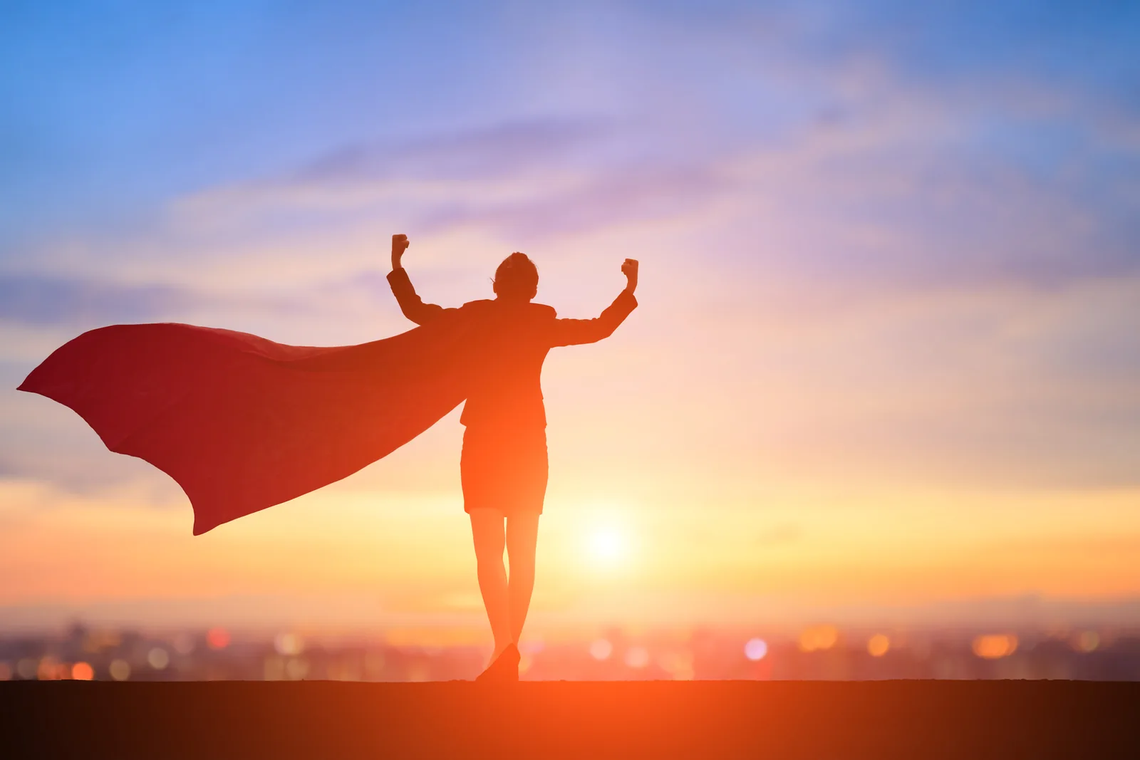 silhouette of woman with superhero cape in fron tof the sun
